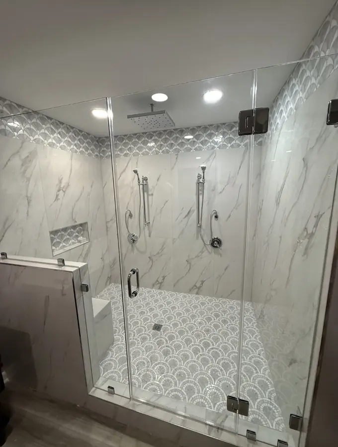 Finished glass-enclosed walk-in shower with rain head, hand showers and tiled bench
