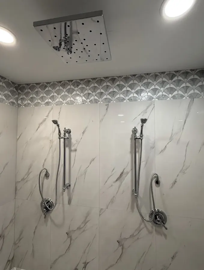 Ceiling rain shower head and two hand-shower stations on marble-look tile