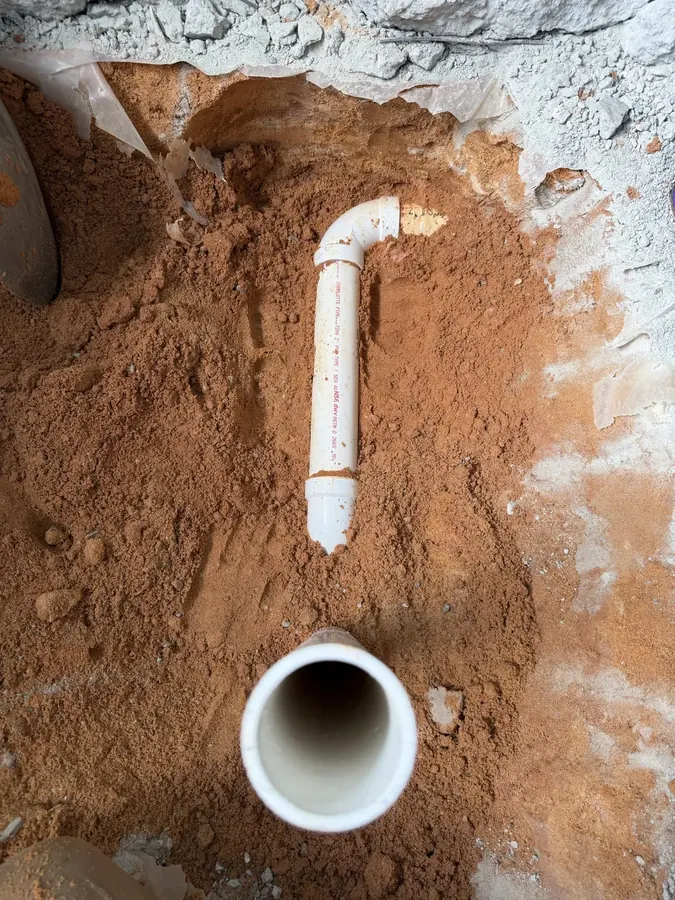 New white PVC drain pipe set in an opening cut through a concrete slab