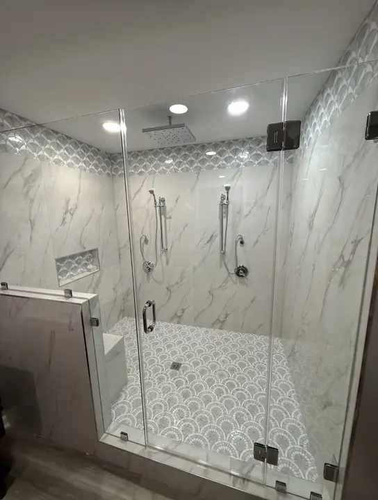 Finished glass-enclosed walk-in shower with rain head, hand showers and tiled bench