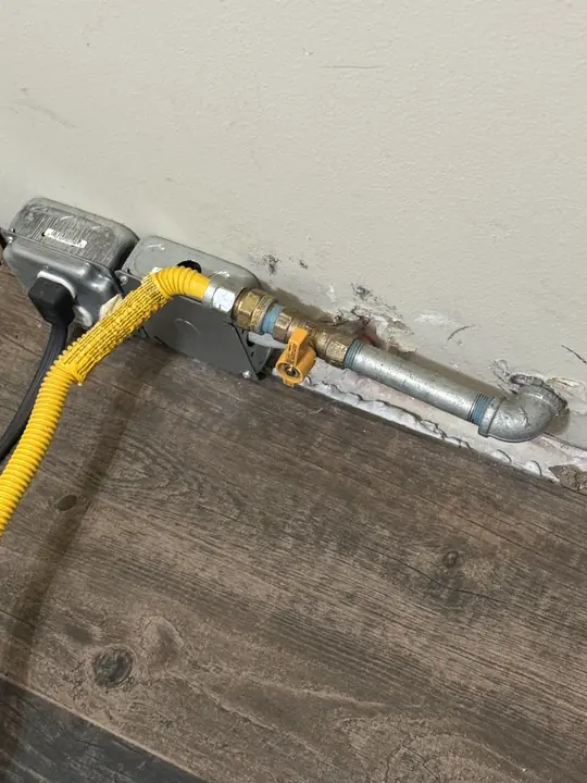 New gas shutoff valve with yellow handle and yellow coated flexible gas connector at a wall