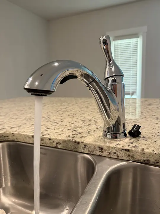 New chrome pull-down kitchen faucet running over a stainless double sink