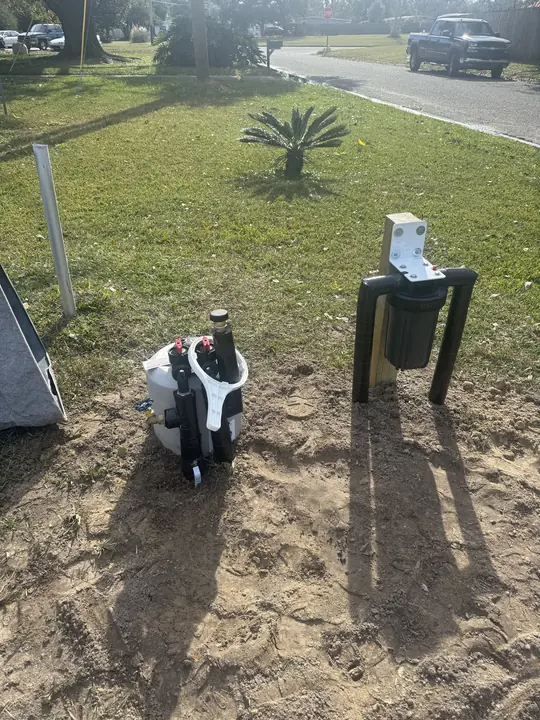 Water filter housing mounted on a post beside a water treatment unit in a front yard