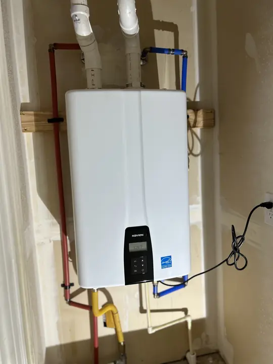 Finished indoor tankless water heater mounted on a wall with gas, water and vent connections