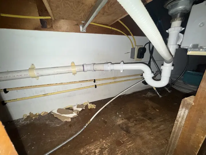 New white PVC tub drain, overflow and trap seen from under the floor
