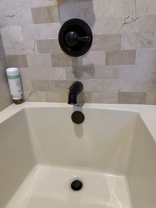 Oil-rubbed bronze tub and shower valve trim, tub spout and drain on a tiled tub