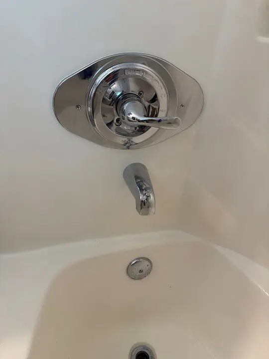 Chrome single-handle tub and shower valve with tub spout on a white surround