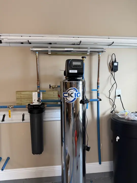 Close view of a stainless water conditioning tank with copper piping and a filter housing