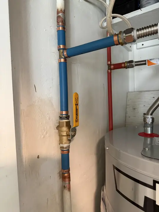 New brass shutoff valve and blue and red PEX supply lines above a water heater