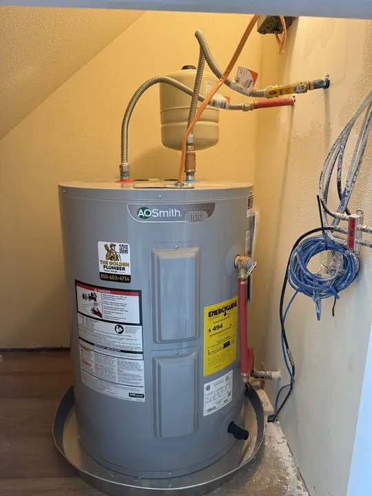 Compact A. O. Smith electric water heater with expansion tank installed under a staircase
