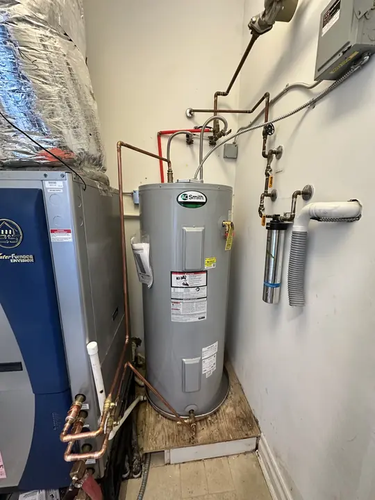 New A. O. Smith electric water heater with copper piping in a mechanical room beside a geothermal unit