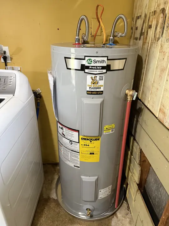 New A. O. Smith ProLine electric water heater with drain pan beside a washing machine