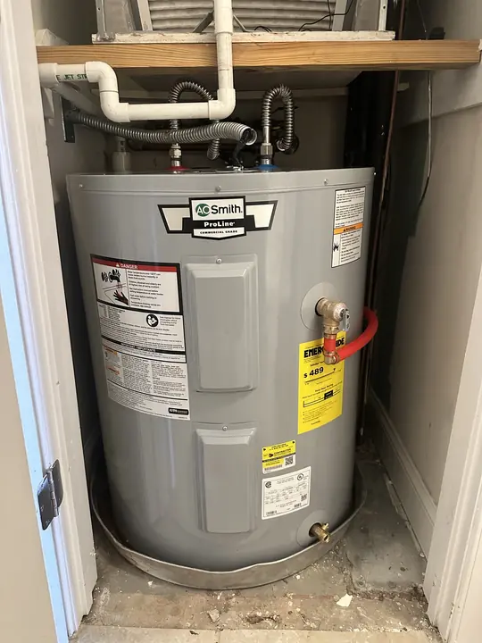 Compact A. O. Smith ProLine electric water heater with drain pan under an air handler platform